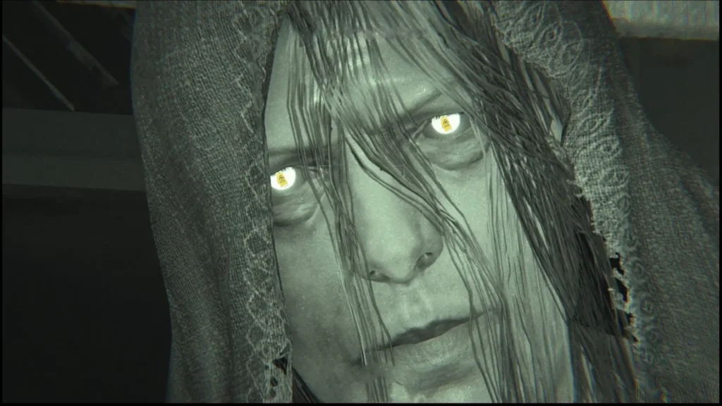 Primer plano de un rostro demacrado con ojos brillantes bajo un velo oscuro en Outlast 2.