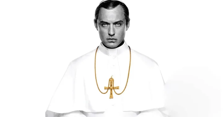 Jude Law, en su papel protagonista en The Young Pope, posando a cámara en blanco y negro sobre un fondo blanco.