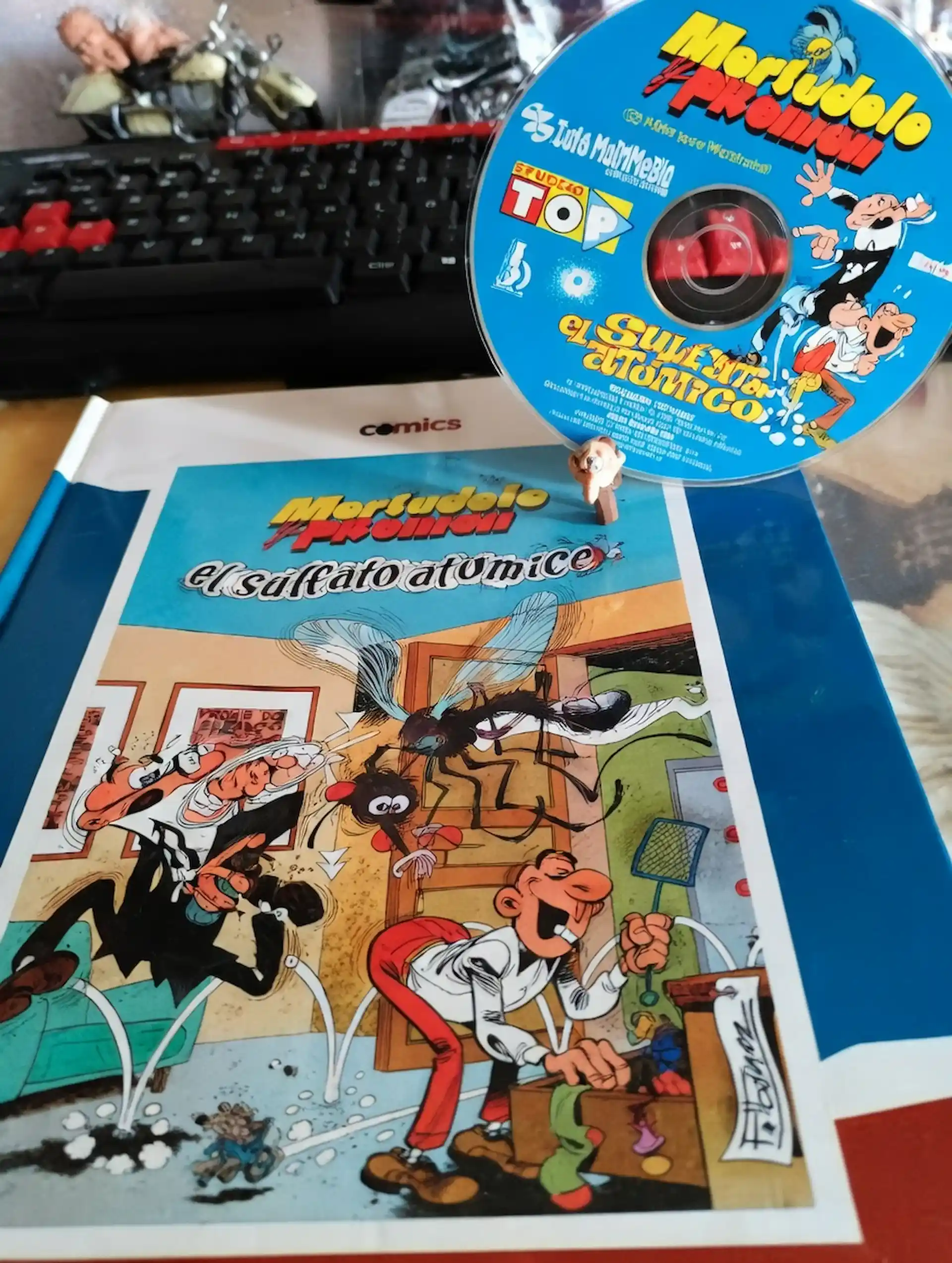 Copia física de Mortadelo y Filemón: El sulfato atómico con su CD-ROM y el cómic original sobre una mesa.