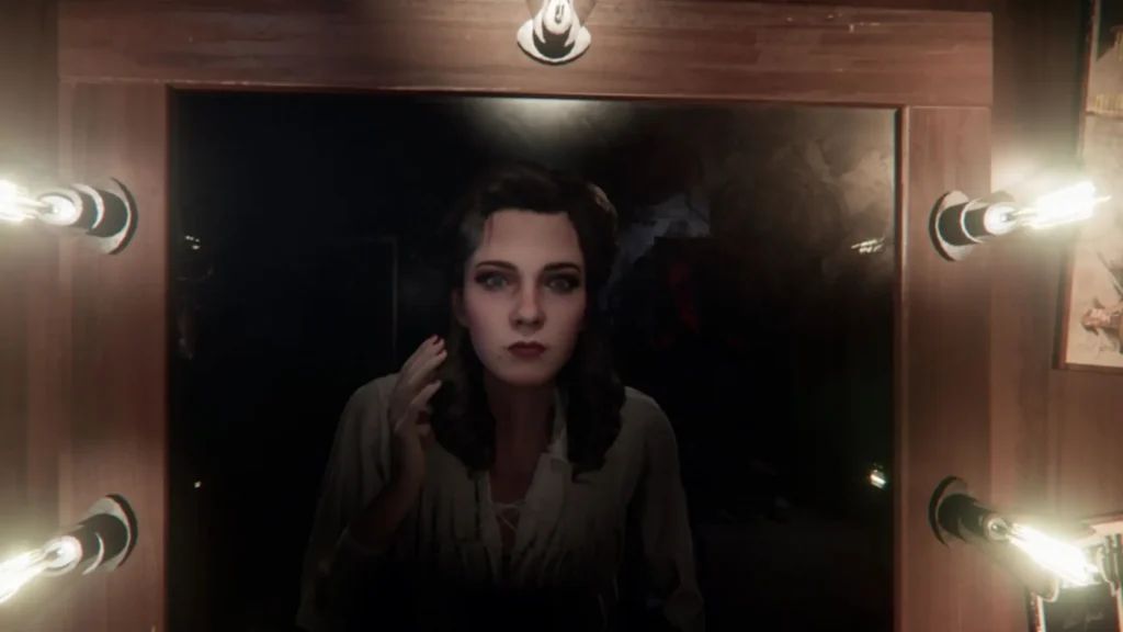Una actriz de Layers of Fear 2 se mira al espejo del camerino iluminado, con gesto tenso y sombras acechando detrás.