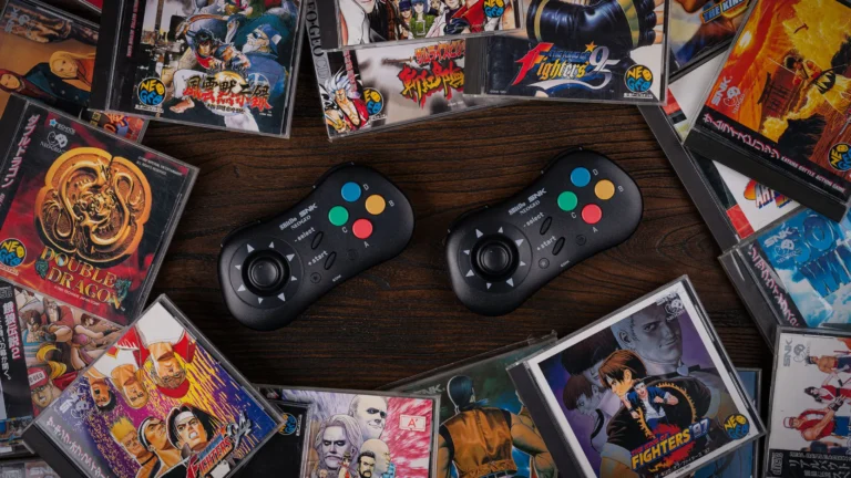 Varios juegos de Neo Geo esparcidos por una mesa junto a un par de mandos de esa consola.