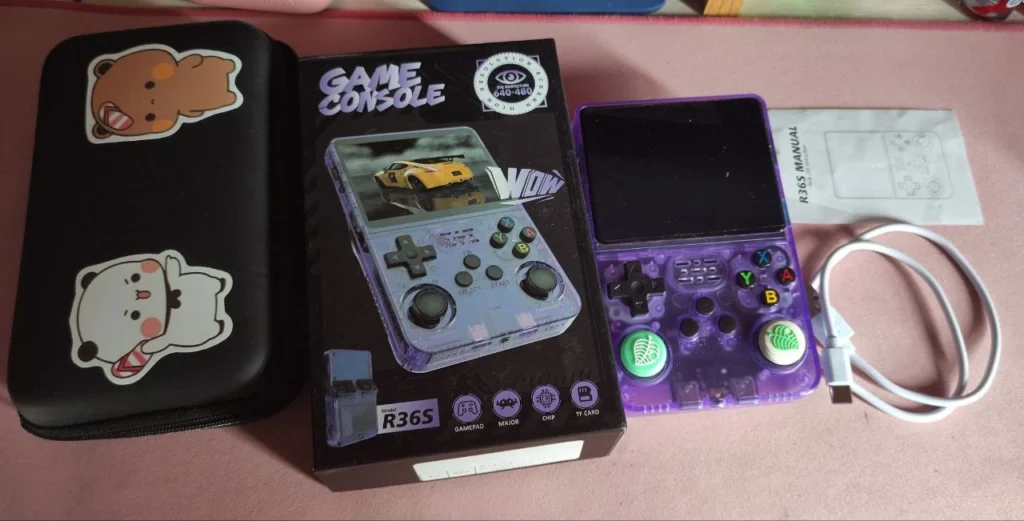 Consola R36S - metemos bajo el microscopio a la máquina del momento 2 Consola R36S, foto de la caja en la que venía. Cuenta con un cable de carga y manual de usuario. También aparece una funda decorada por la autora del texto.