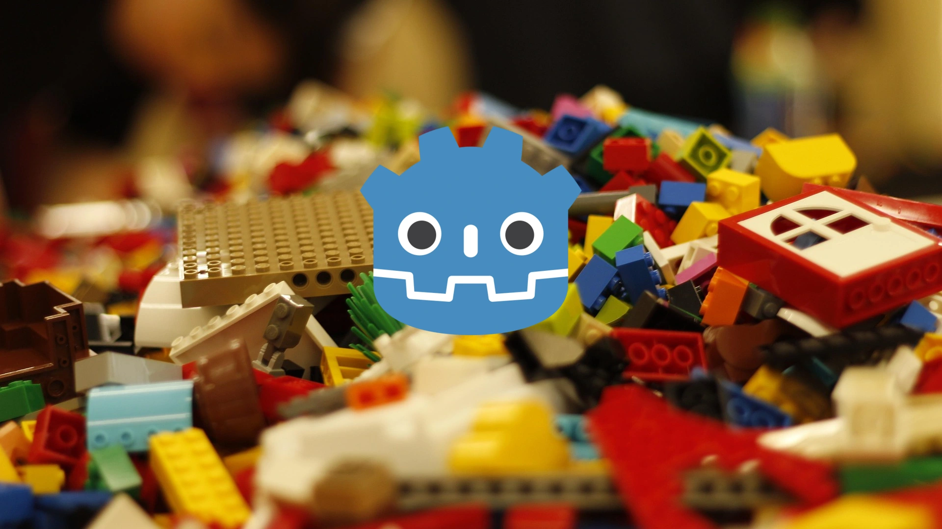 Logo de Godot sobre un montón de piezas de LEGO de distintos colores.