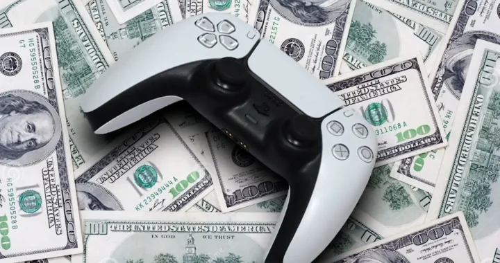 Mando DualSense sobre billetes de dólar simbolizando el precio de los videojuegos en la industria actual.