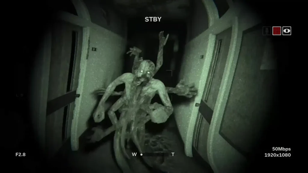 Criatura deformada con múltiples brazos avanza por un pasillo oscuro bajo la visión nocturna en Outlast 2.