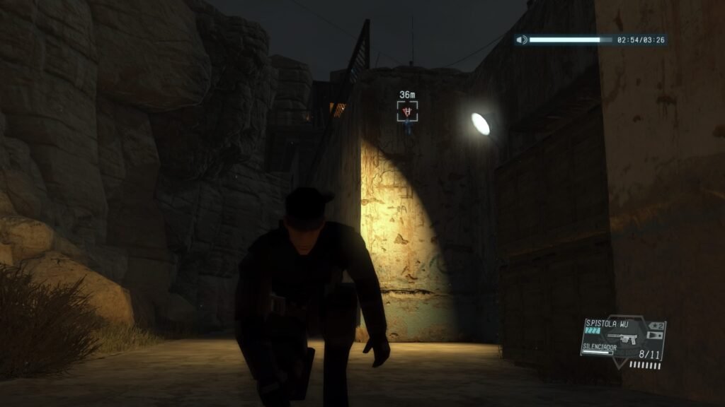 Big Boss se agacha entre sombras en una base rocosa nocturna, preparándose para infiltrarse sigilosamente en The Phantom Pain.