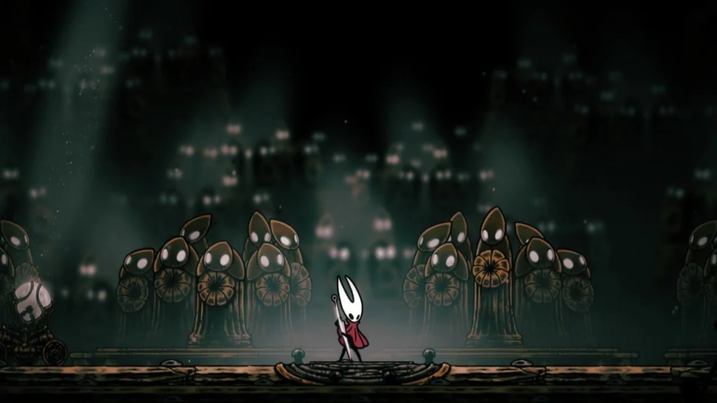 Hornet se enfrenta a una multitud de enemigos con cabezas de campana en una oscura mazmorra de Silksong.