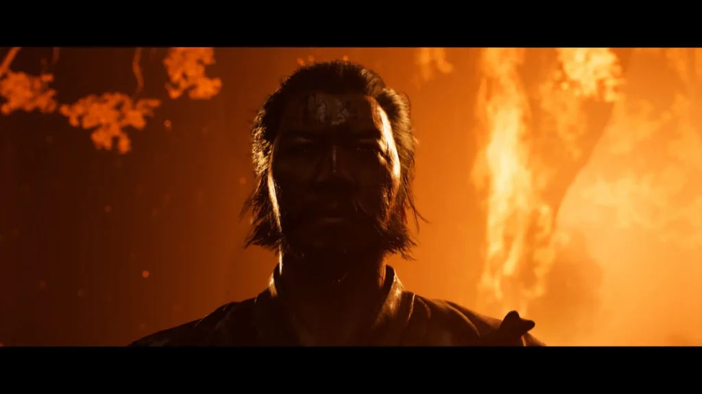 Escena cinematográfica de Ghost of Yotei donde un samurái emerge entre llamas nocturnas, con el rostro en sombras y un entorno ardiendo.
