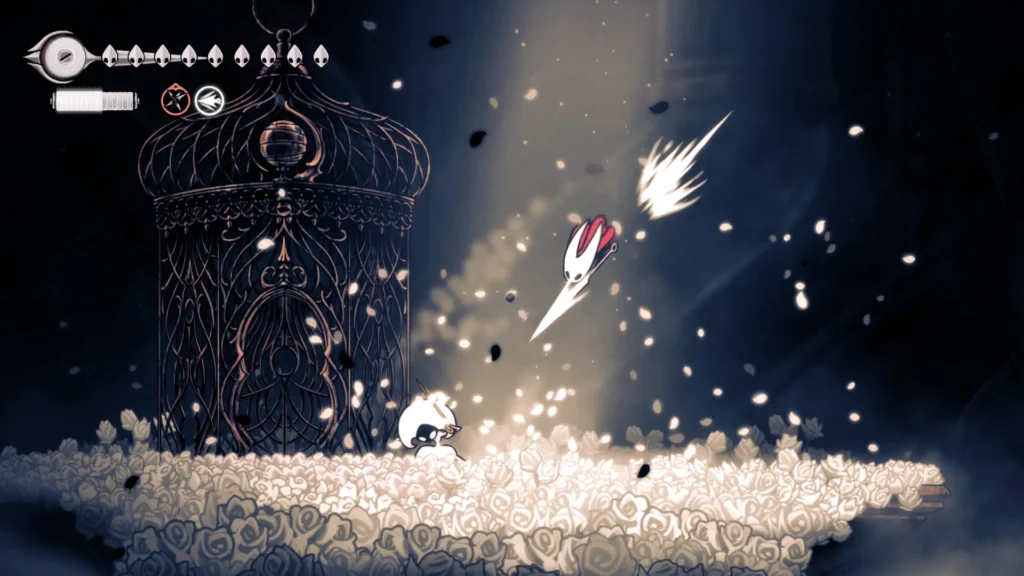 Combate en Hollow Knight: el Caballero esquiva proyectiles frente a una jaula en un escenario onírico cubierto de flores blancas y partículas luminosas.