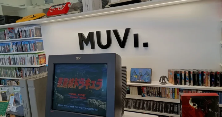 Una televisión antigua reproduciendo un Castelvania. Estanterías llenas de juegos, consolas sobre repisas y el logo del museo en la pared.