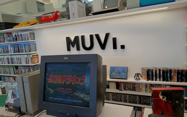 Una televisión antigua reproduciendo un Castelvania. Estanterías llenas de juegos, consolas sobre repisas y el logo del museo en la pared.