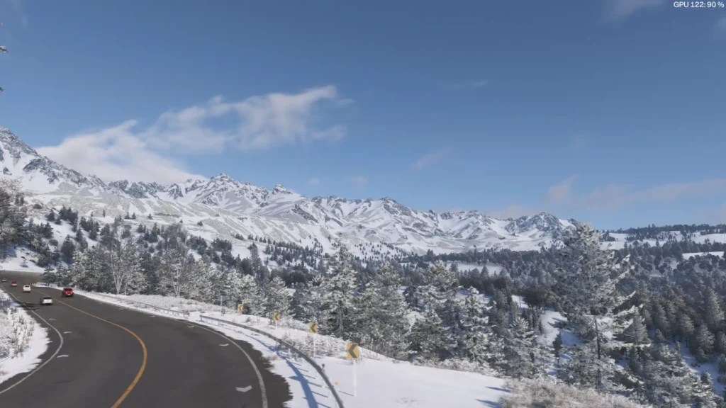 Carretera de montaña nevada en Forza Horizon 6 flanqueada por pinos bajo un cielo azul despejado.
