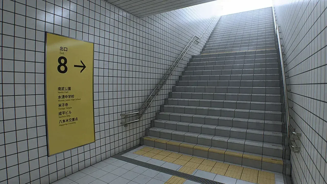 Exit 8: escalera hacia la superficie junto al cartel amarillo de la Salida 8 y su lista de lugares cercanos.